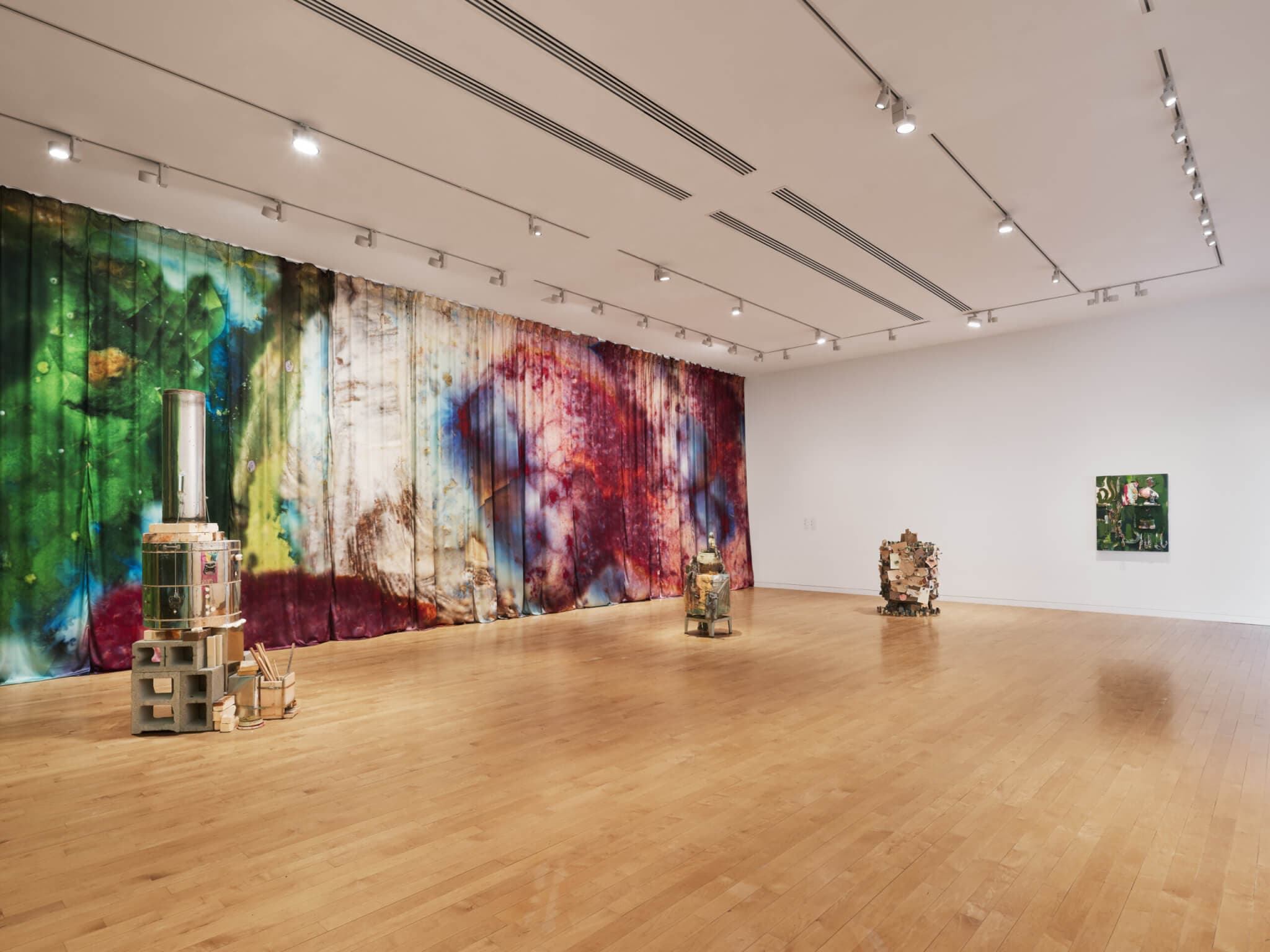 A large silk artwork covers a gallery wall behind kiln-sculptures.