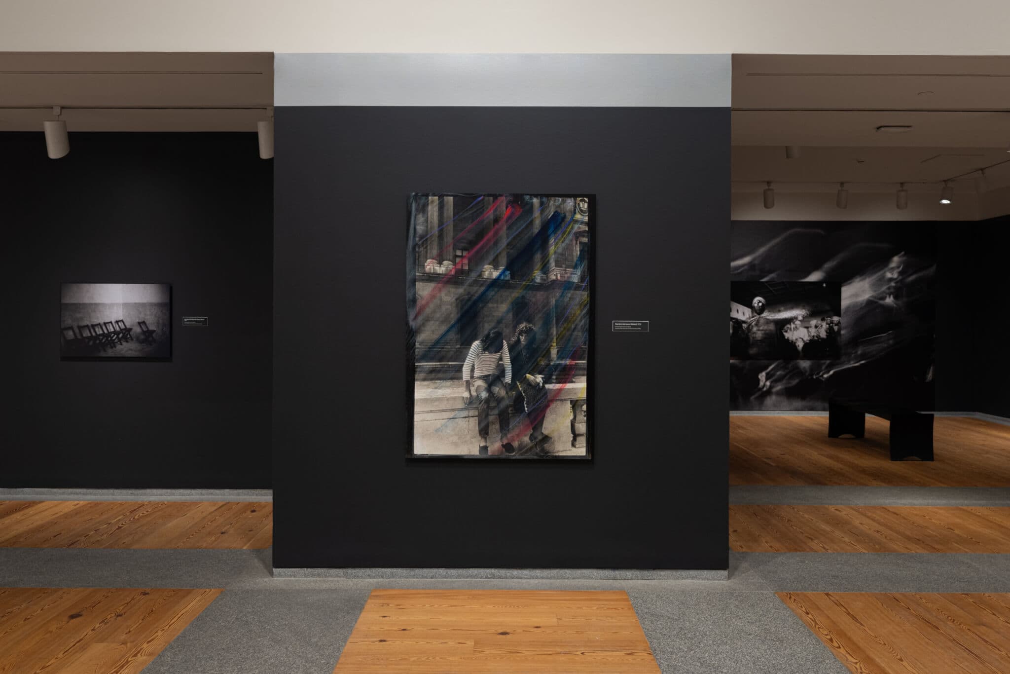 Large-format photographs on a black gallery wall.