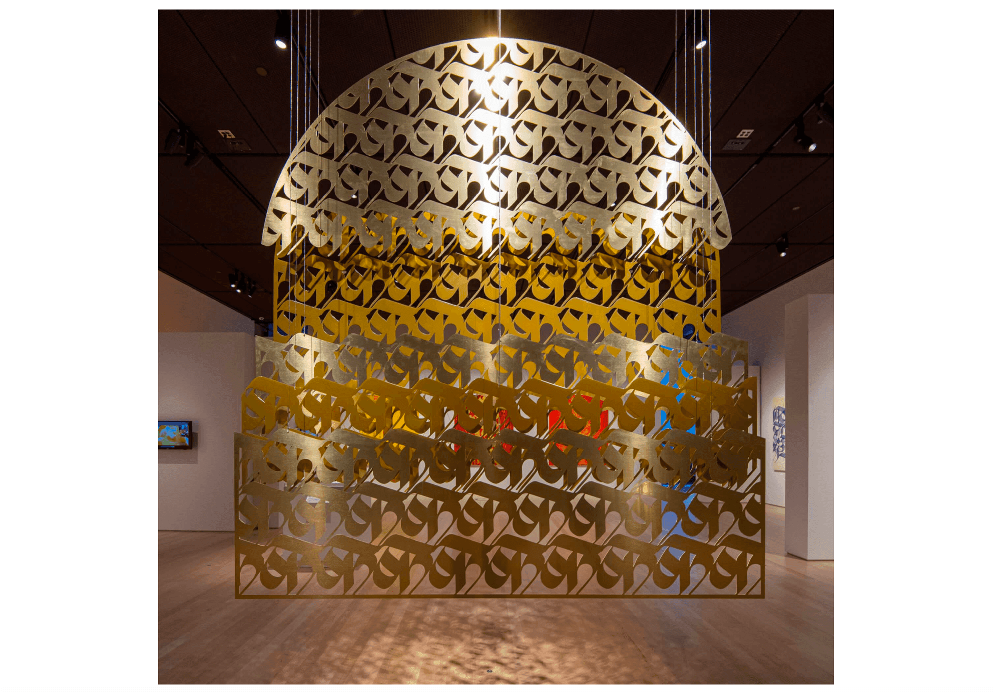 A close-up of a metal sculpture with a design motif suspended by wires.